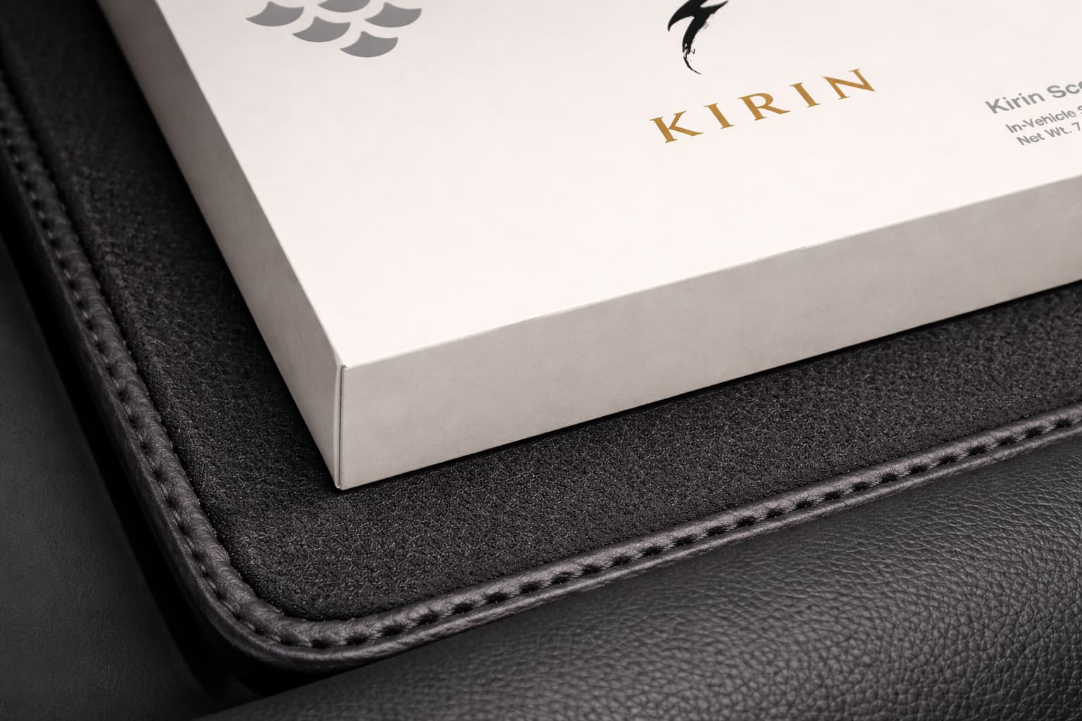Kirin Scent minimalist car fragrance packaging on a premium black Alcantara and leather car interior surface.